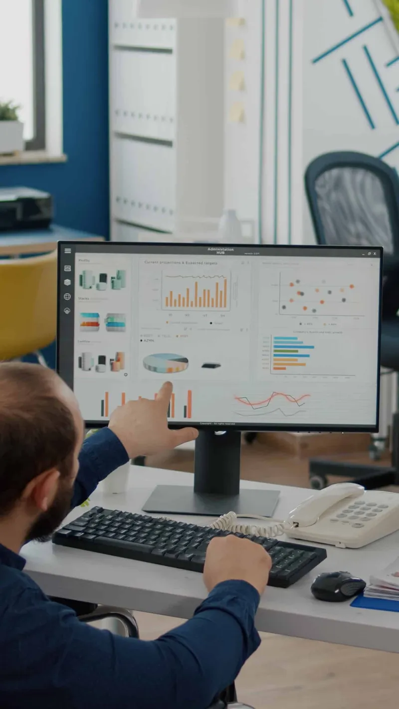 An analyst reviewing pharmacy plan charts on a desktop dashboard