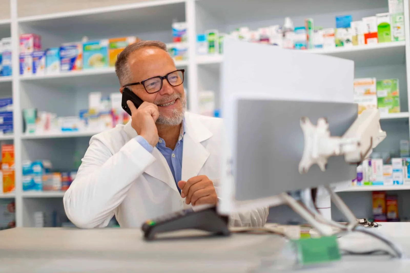 A pharmacist taking a call at the pharmacy counter